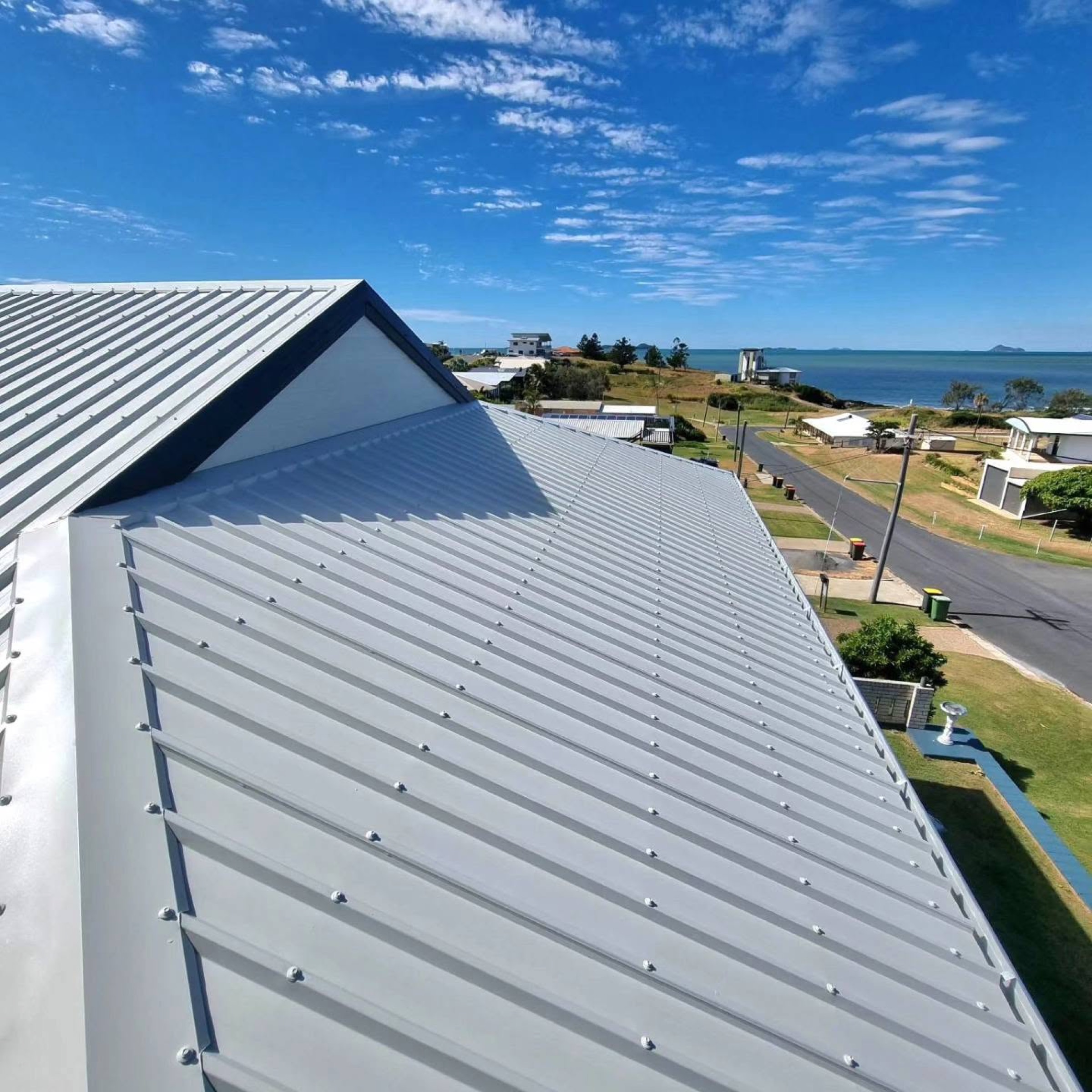 A newly coated metal roof with the coastline and township beyond it
