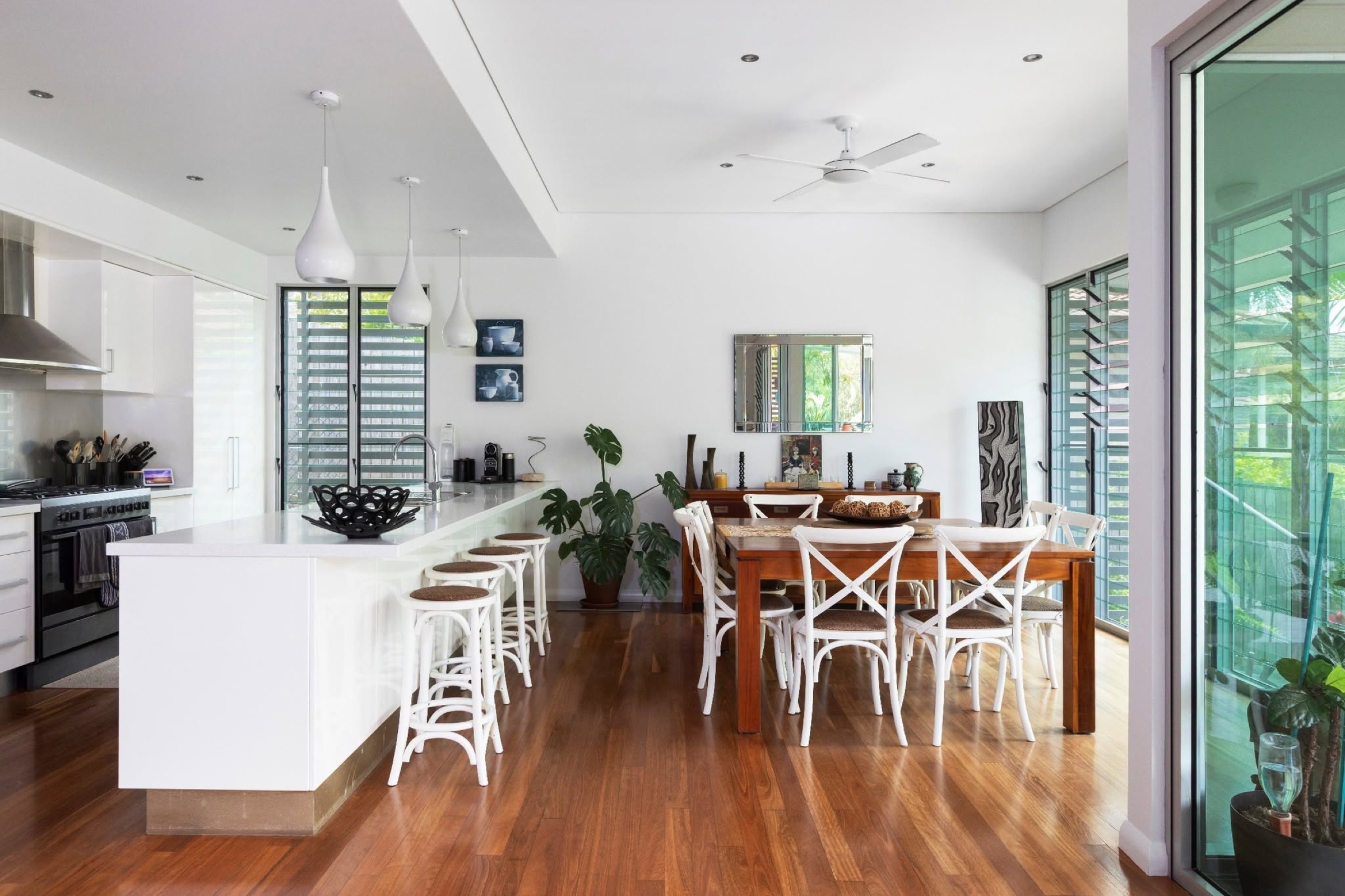 A kitchen and dining area finished in white with timber flooring and large windows