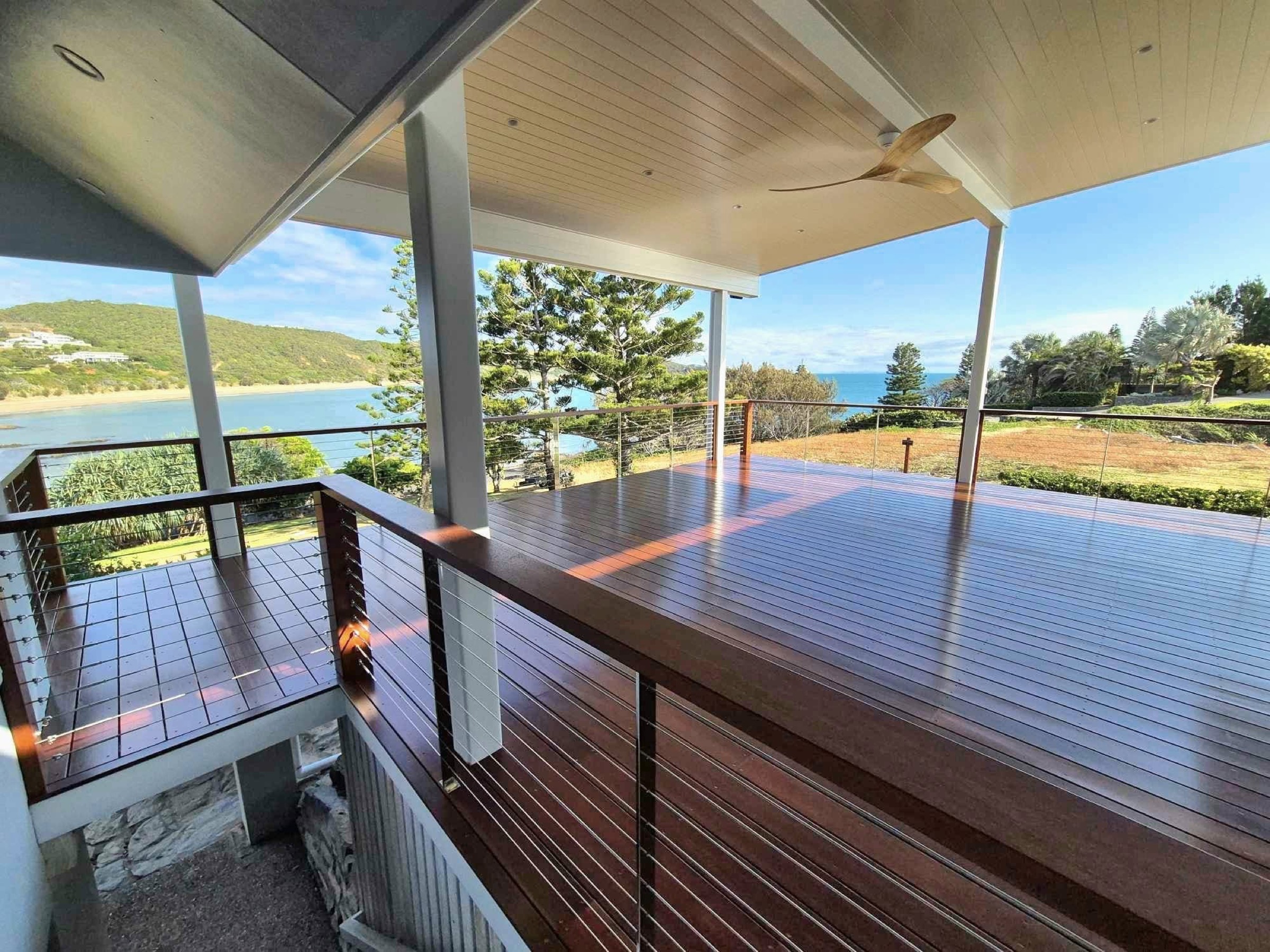 A timber deck freshly coated, looking out over a headland and the sea