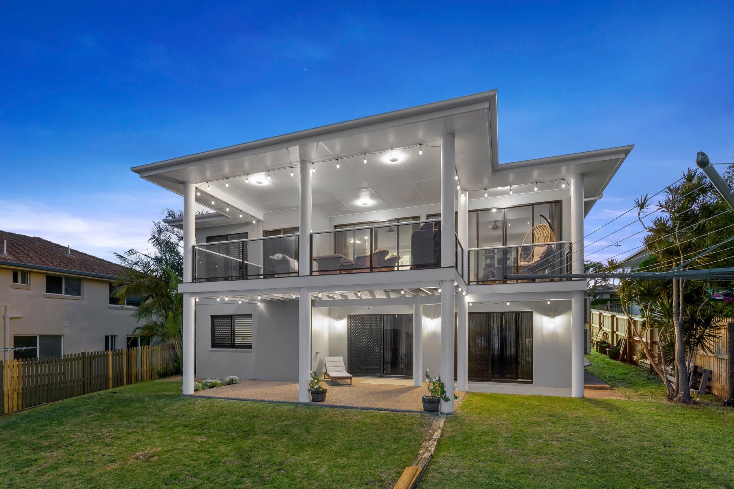 A two storey Queensland home at dusk with freshly painted walls and warm interior lights