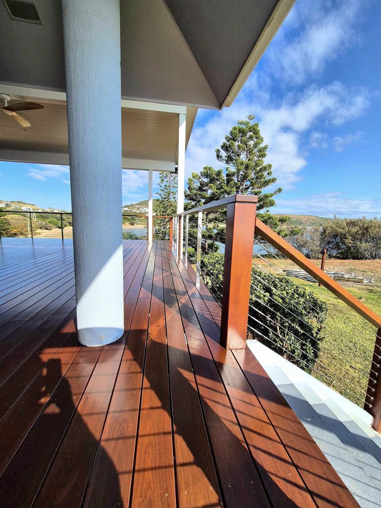 A timber deck under a verandah with a fresh coating and a sea view beyond