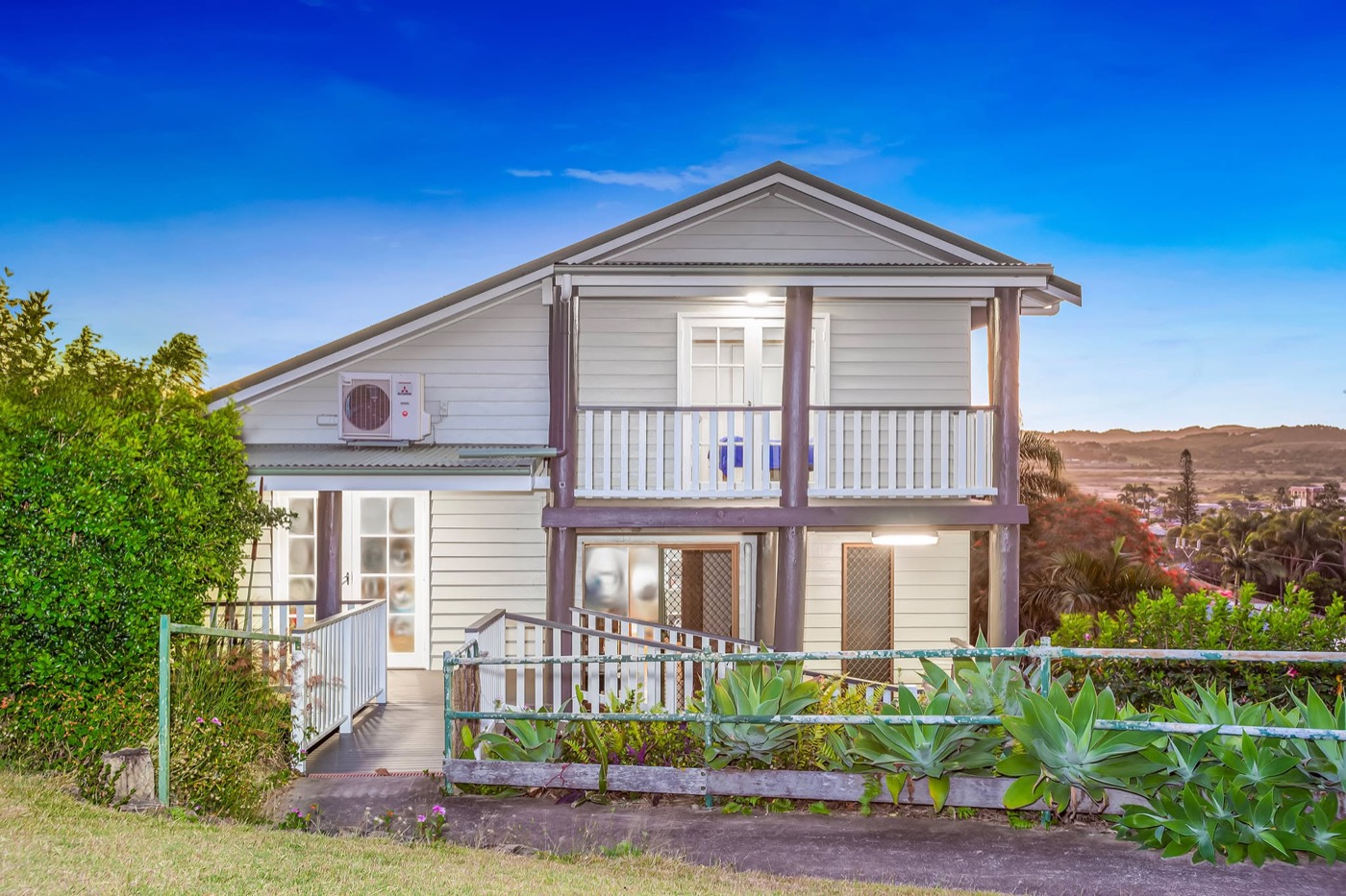 A weatherboard cottage in fresh white paint with a blue sky behind it