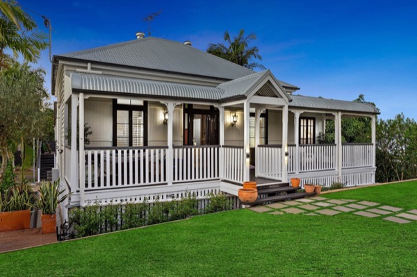 A white weatherboard Queenslander with a wide verandah and white balustrade