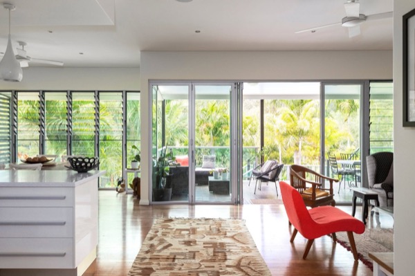 An open plan living and kitchen space in white with glass doors to the yard