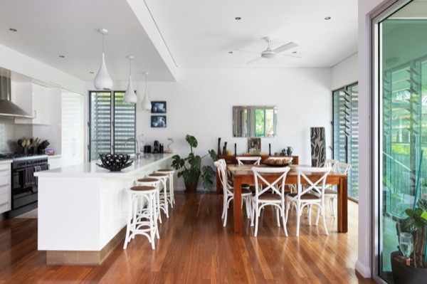 A kitchen and dining area finished in white with timber flooring and large windows