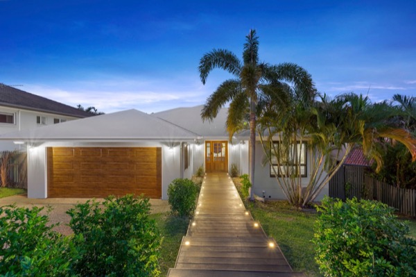 A home at dusk with a lit garden path leading to a timber front door