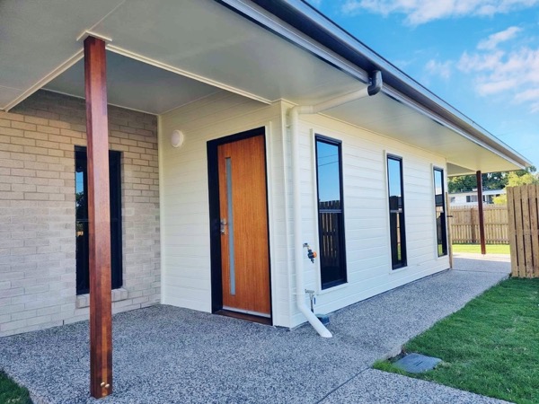 The entry of a new build with white walls, a timber post and a black door
