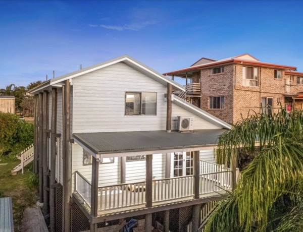 A highset weatherboard home with coated cladding and white trims