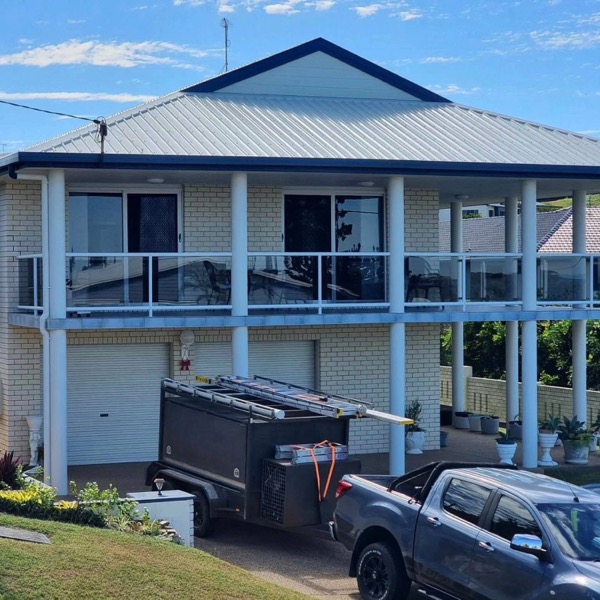 A two storey home with a ute and trailer parked in the driveway