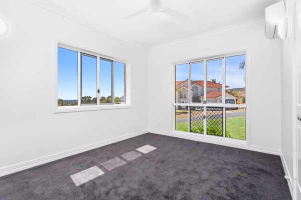 An empty room in fresh white with grey carpet and windows to the garden