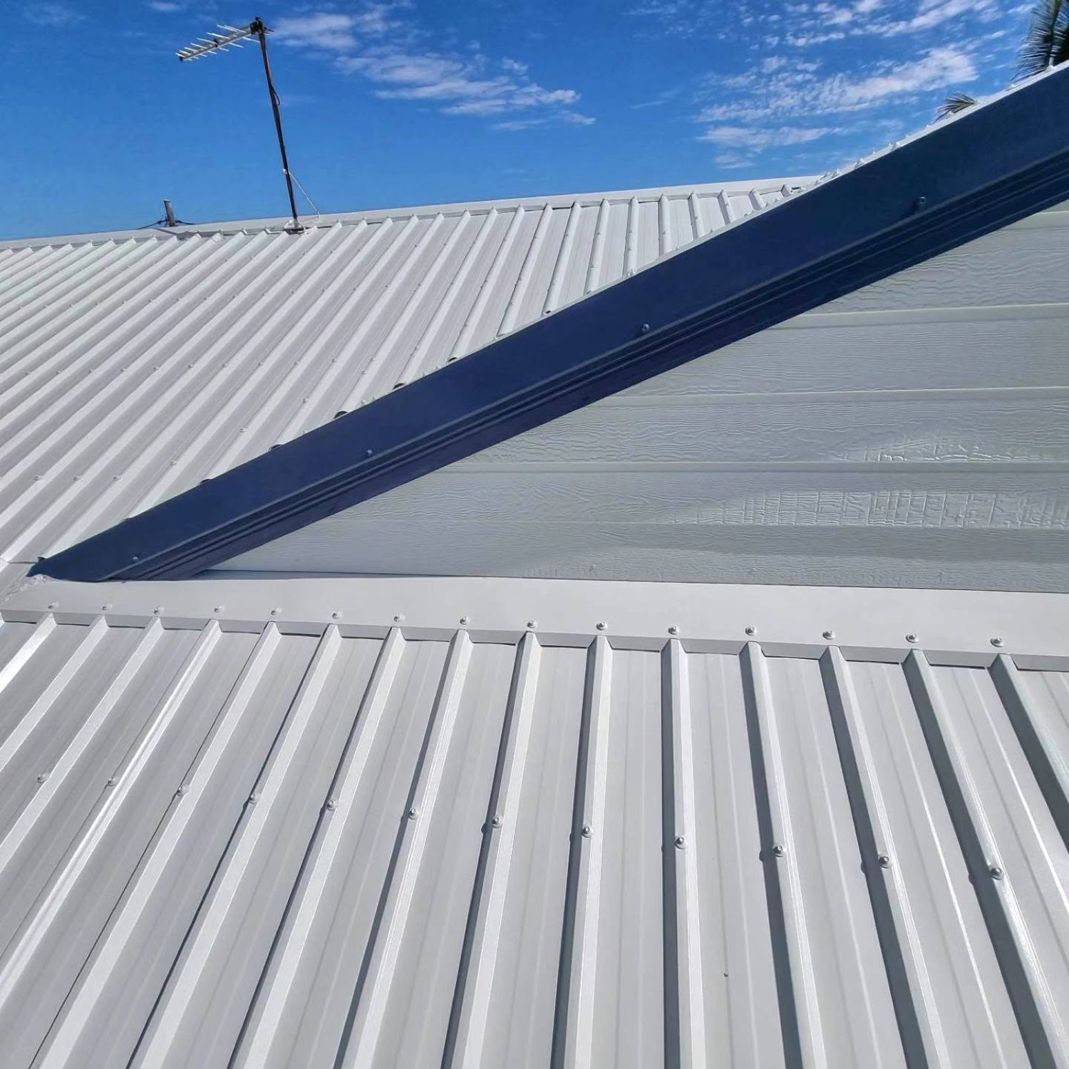 A metal roof in pale grey coating with a charcoal ridge line