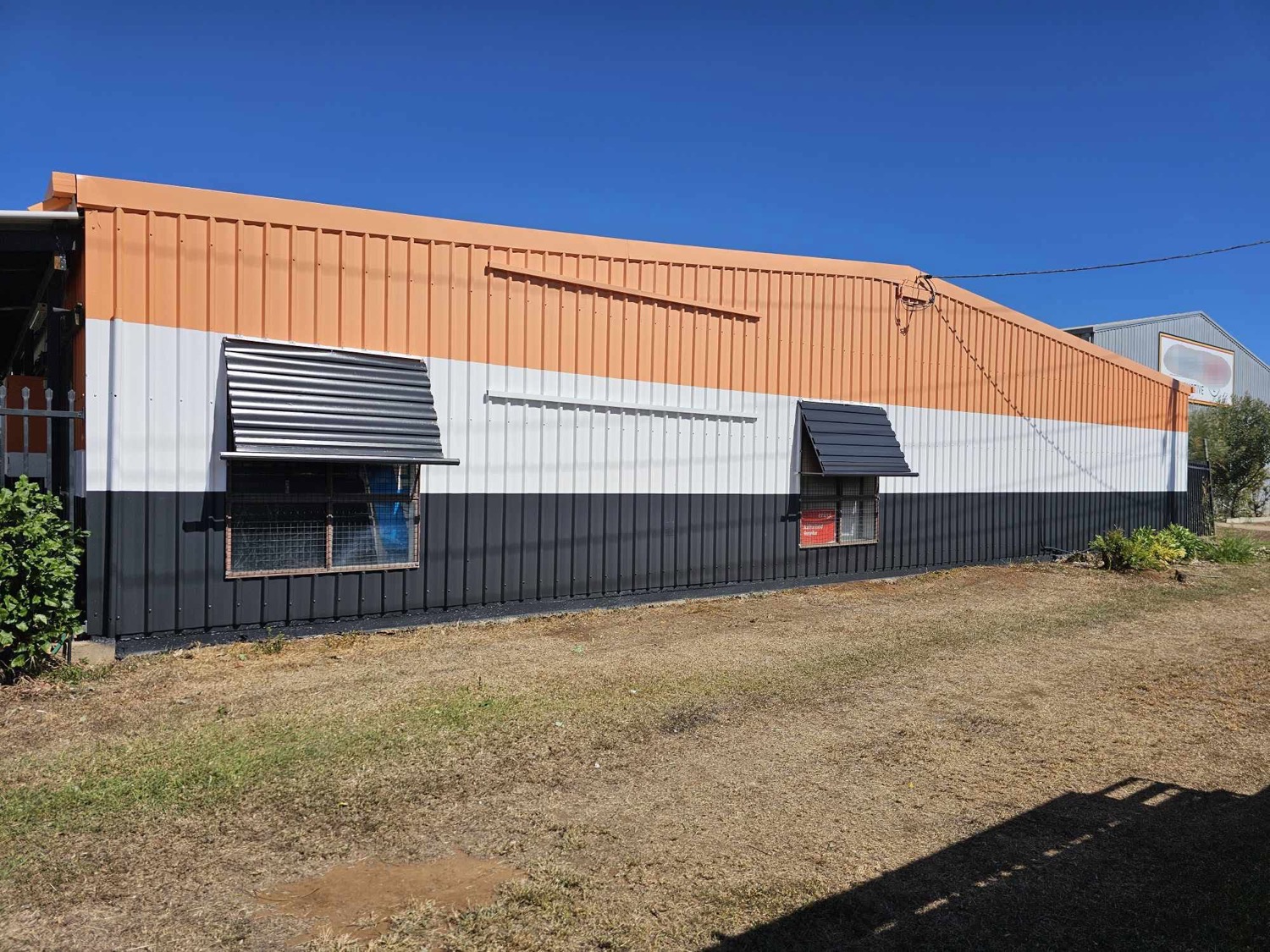 A commercial shed in orange, white and charcoal bands
